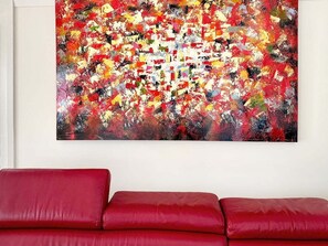 Un canapé rouge dans une pièce où est accrochée une peinture abstraite aux couleurs vives.