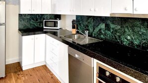 A kitchen with white cabinets, a black countertop, a microwave, and a dishwasher. - Gurwood Stay - All of the Comforts (Wagga Wagga)