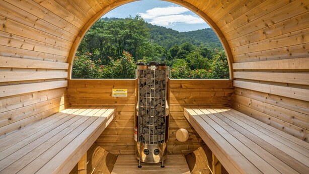 Uma sauna com bancos de madeira e vista para uma encosta arborizada.