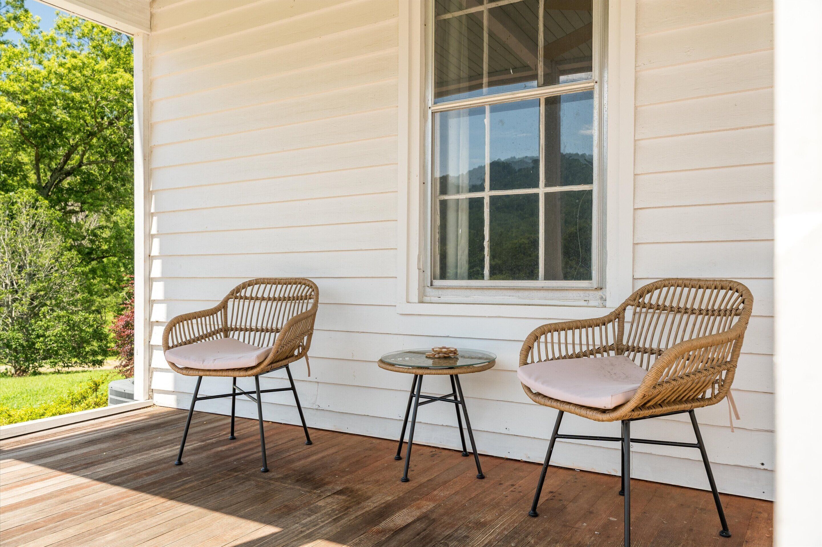A porch with two wicker chairs and a small round table.