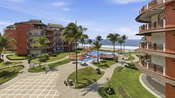 Ein Resort mit Pool, Palmen und Blick auf den Strand.