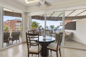 Ein Zimmer mit einem runden Tisch, Stühlen, großen Fenstern und einem Deckenventilator.