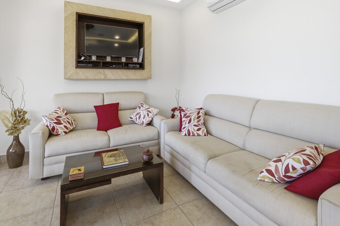 Uma sala de estar com dois sofás, uma mesa de centro e uma TV de tela plana na parede.