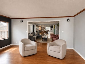 A spacious living area with a wooden floor, two armchairs, a sofa, and a dining area in the background. - The Rad in Town (Houston)