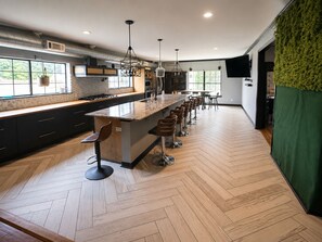A modern kitchen with a central island, bar stools, and a herringbone wood floor. - The Rad in Town (Houston)