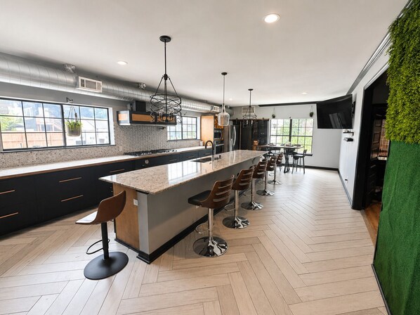A modern kitchen with a large island, bar stools, and a dining area with a view. - The Rad in Town (Houston)