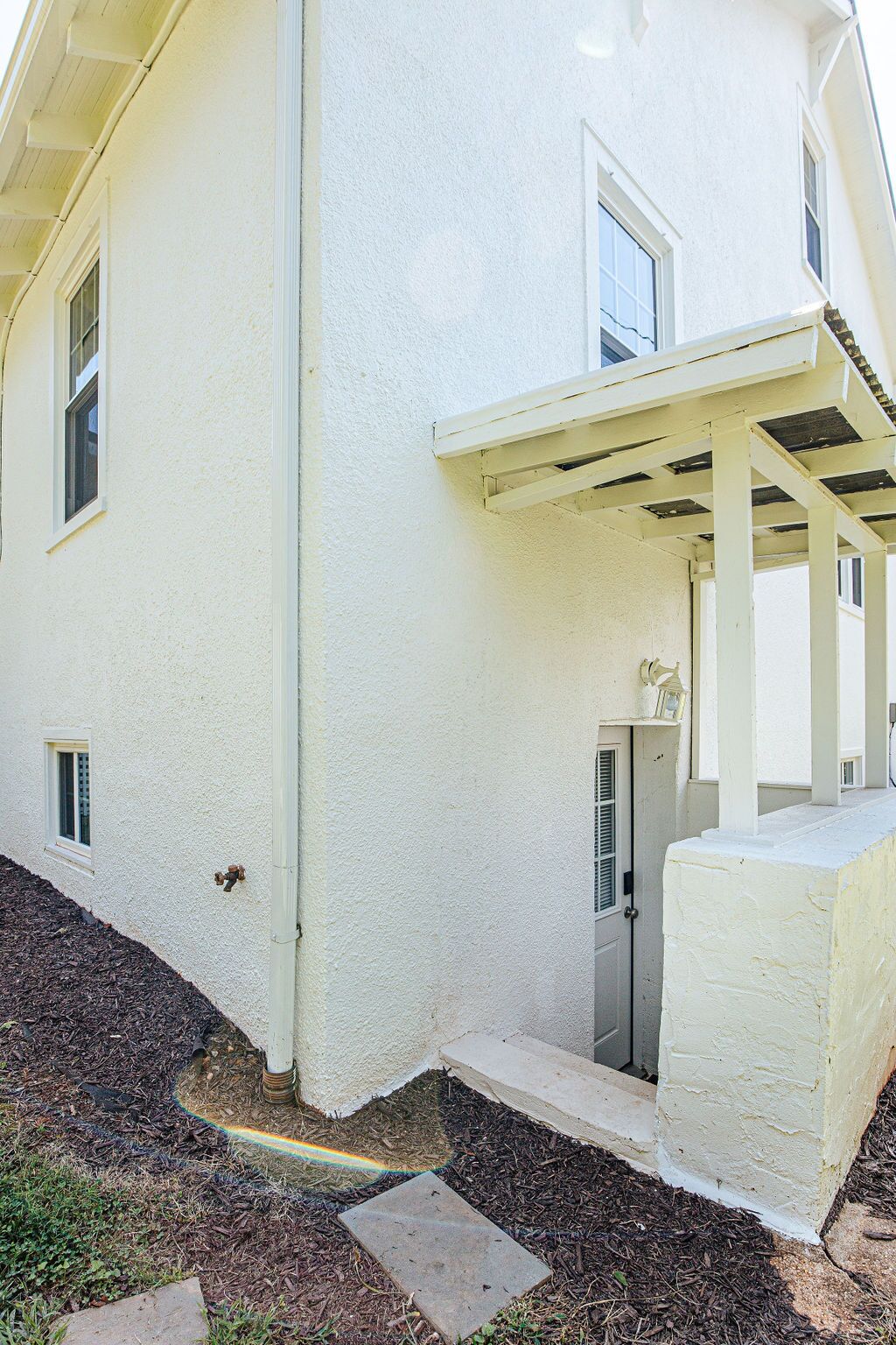 A white building with a covered porch, a door, and a small window.