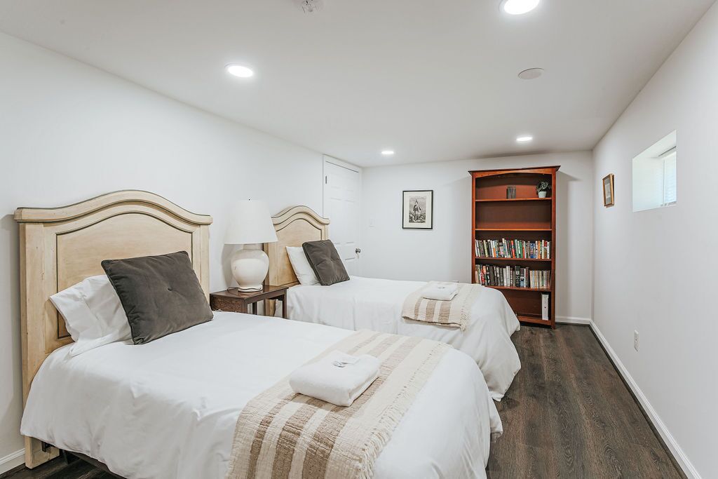Habitación de hotel con dos camas, una estantería y una puerta.