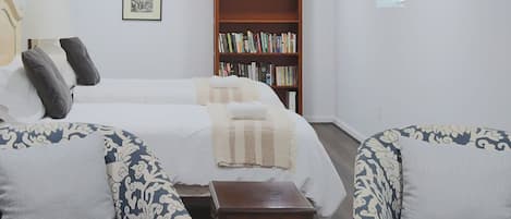 Een kamer met een bed, twee gestoffeerde banken, een kleine tafel, een boekenkast en een lijst met een afbeelding aan de muur.
