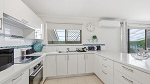 Une cuisine moderne avec des meubles blancs, un four encastré, un micro-ondes, un évier et une fenêtre donnant sur un beau paysage.