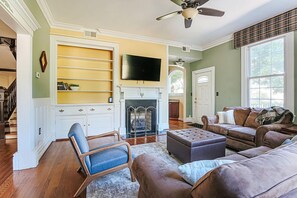 Una sala de estar con chimenea, televisor y un amplio ventanal.