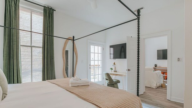 A bedroom with a four-poster bed, a desk, a chair, and a television. - Daydream & Draft (Staunton)