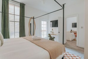 Un dormitorio con cama con dosel, un escritorio, una silla y un televisor.