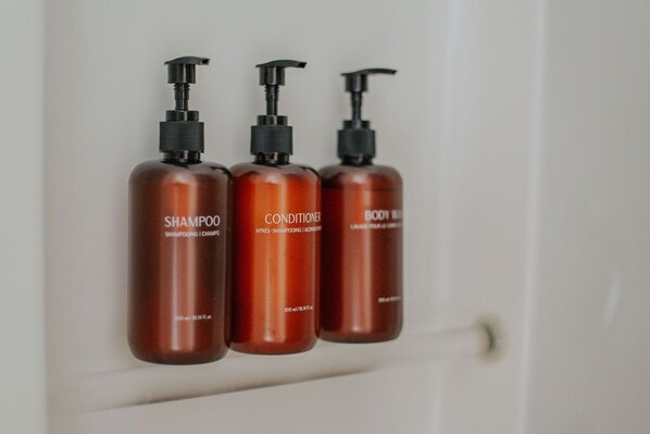 Three brown bottles of shampoo, conditioner, and body wash on a white surface. - Daydream & Draft (Staunton)