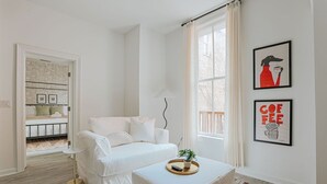 A minimalist room with a white sofa, a small table with a tray, and two framed pictures on the wall. - Daydream & Draft (Staunton)