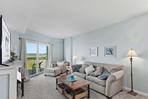 Ein Wohnzimmer mit einer Couch, einem Couchtisch, einer Lampe und Blick durch eine Glastür.