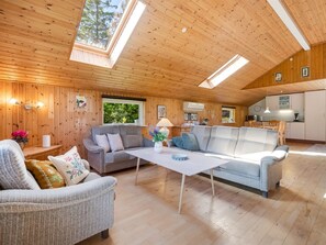 Ein gemütliches Blockhaus-Interieur mit Holzbalkendecke, Essbereich und Küche.
