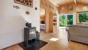 Ein gemütliches Zimmer mit Kaminofen, einer Couch und einem Essbereich mit Holzwänden und einem Kamin aus Ziegelsteinen.