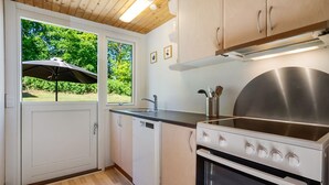 Eine Küche mit Herd, Spüle und Schränken, ein Fenster mit einem Regenschirm und eine Tür.