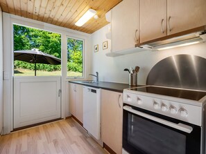 Eine Küche mit Herd, Spüle und Schränken, ein Fenster mit einem Regenschirm und eine Tür.