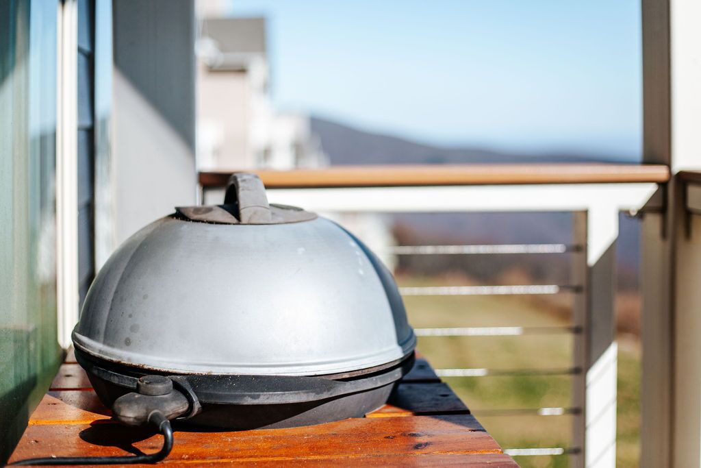 Uma chaleira de metal sobre uma mesa de madeira, em frente a um edifício.