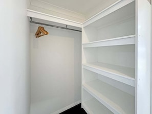 Un armario blanco con estantes abiertos y barra para colgar ropa.