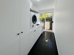 A laundry room with a washing machine, dryer, and a sliding glass door leading to an outdoor area.