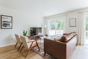 A modern living room with a sofa, chairs, a TV, and a large window. - Fox Hill (Afton)