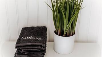 A stack of black towels with the word "Makeup" on them and a white pot with green plants.