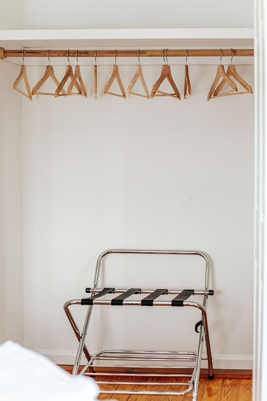A metal drying rack with black straps and a wooden hanger rod above it.