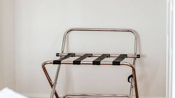 A metal drying rack with black straps and a wooden hanger rod above it.
