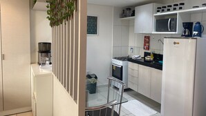 A modern kitchen with white cabinets, a gas stove, a refrigerator, and a microwave. - Bela Hospedagem - Wind Palace 606  (Cabedelo)