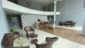 A spacious lobby with wicker furniture, a reception desk, and a staircase. - Bela Hospedagem - Wind Palace 606  (Cabedelo)