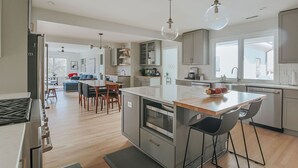 Een moderne keuken met een centraal eiland, roestvrijstalen apparatuur en hanglampen.