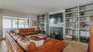 Een moderne woonkamer met een leren bank, een open haard en ingebouwde boekenkasten.