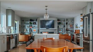 Een moderne keuken met een eettafel, stoelen, een televisie en inbouwplanken.
