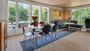 Un interior moderno con comedor, sofá y ventanas grandes.