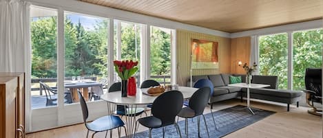 Un intérieur moderne comprenant un coin repas, un canapé et de grandes fenêtres.