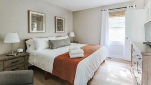 A bedroom with a bed, two bedside lamps, a dresser, a chair, and two framed pictures on the wall. - Hillside Haven (Faber)