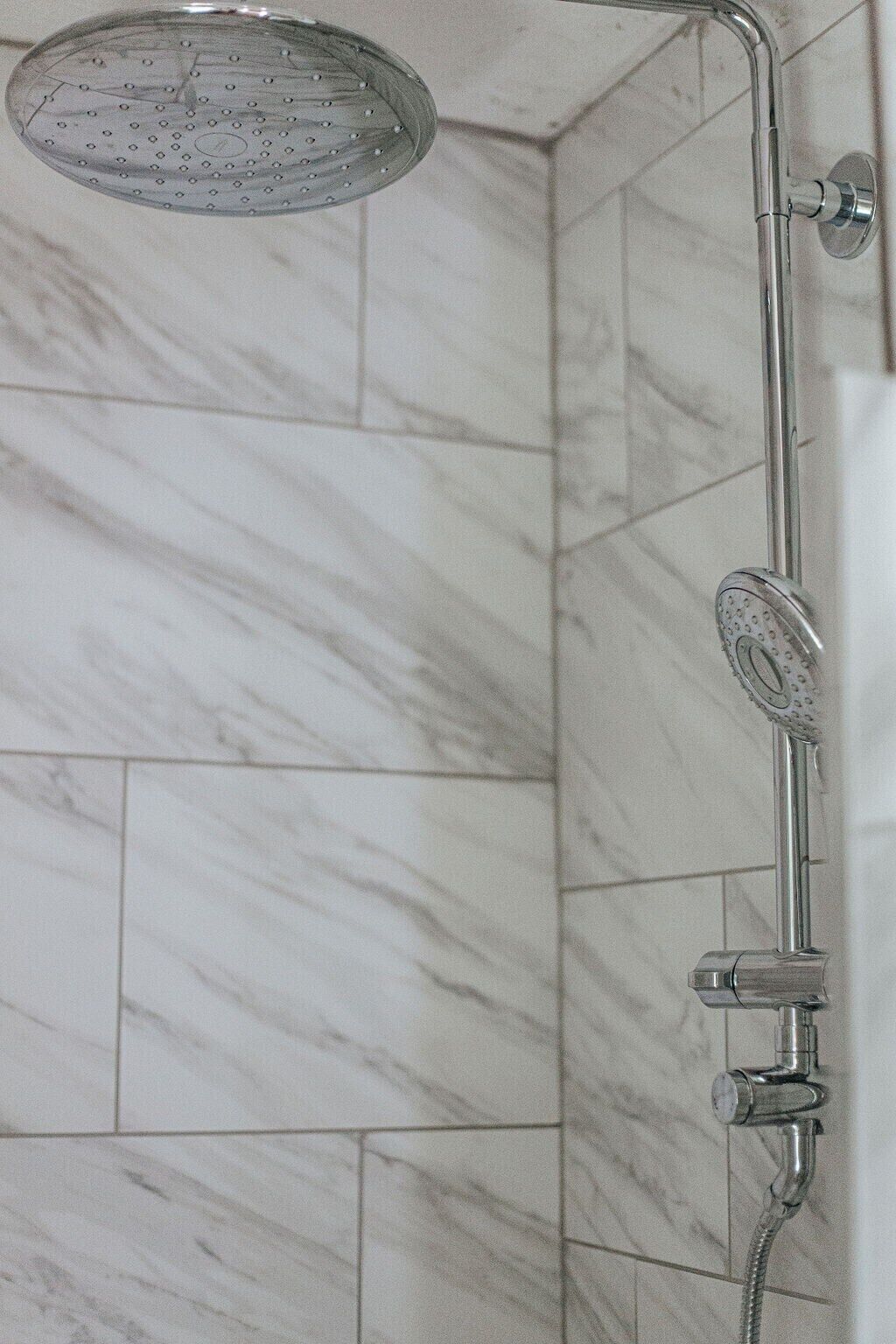Eine Dusche mit Handbrause und Armaturen an der Wand.