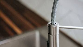 A kitchen faucet with a flexible hose and a metallic finish.