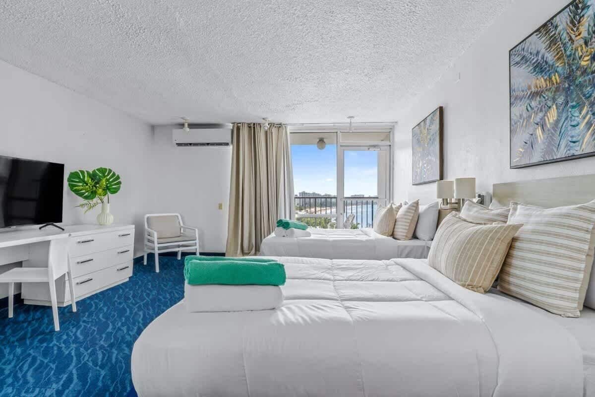 Habitación de hotel con cama, escritorio, silla, televisor y ventana con vistas.