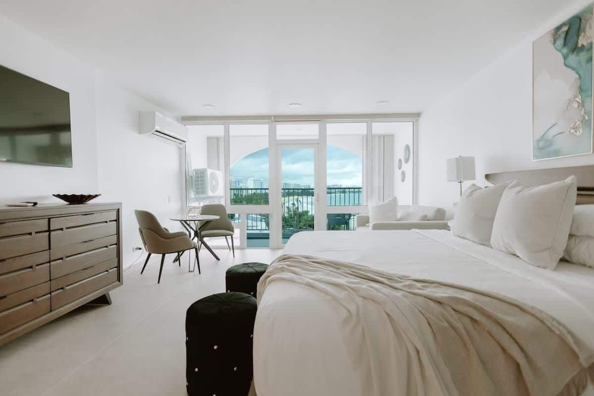 Una habitación de hotel moderna con una cama grande, un escritorio, una silla y un balcón con vistas.