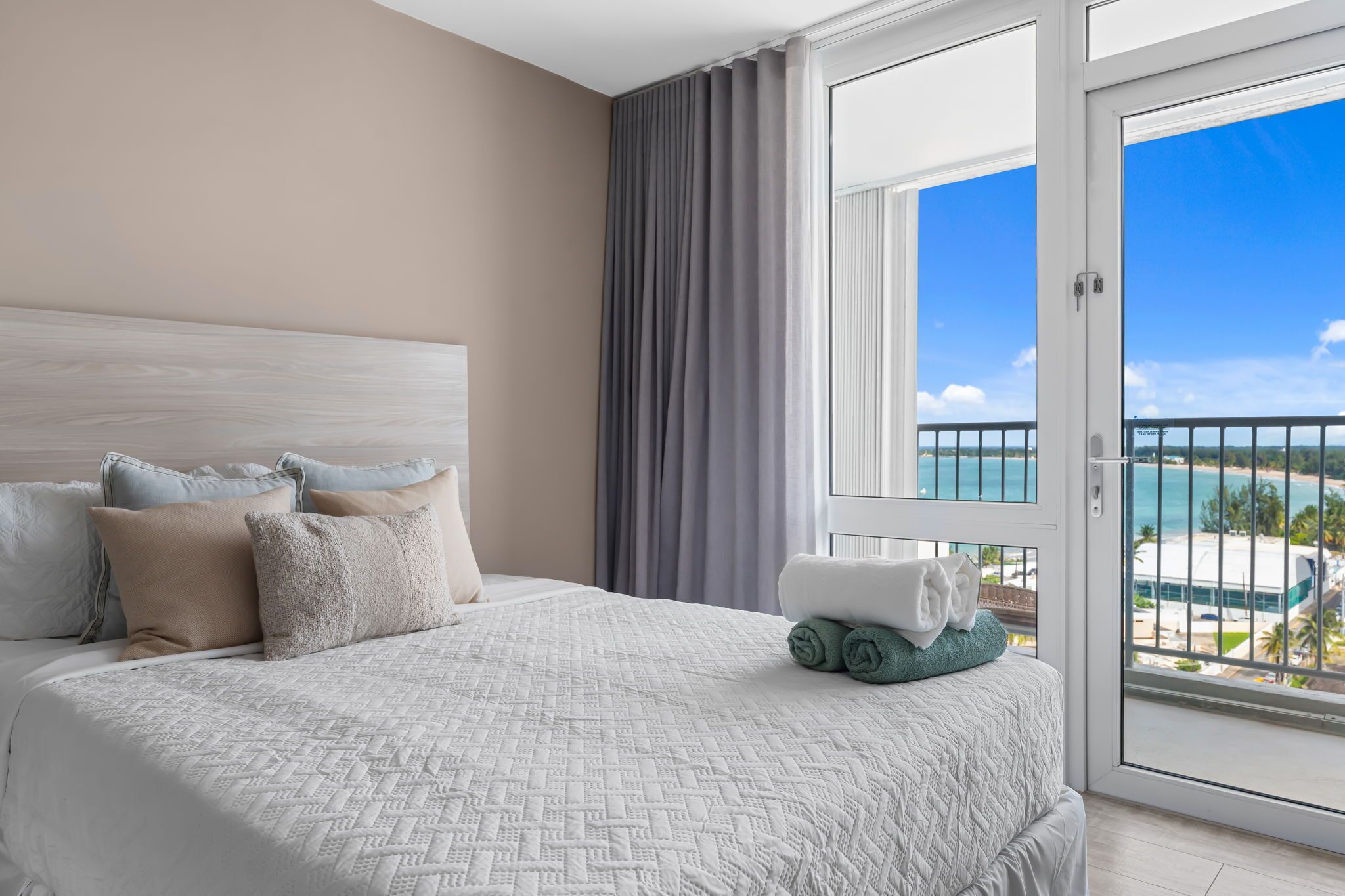 Une chambre d’hôtel avec un grand lit, une vue sur la plage et un balcon doté d’une balustrade.