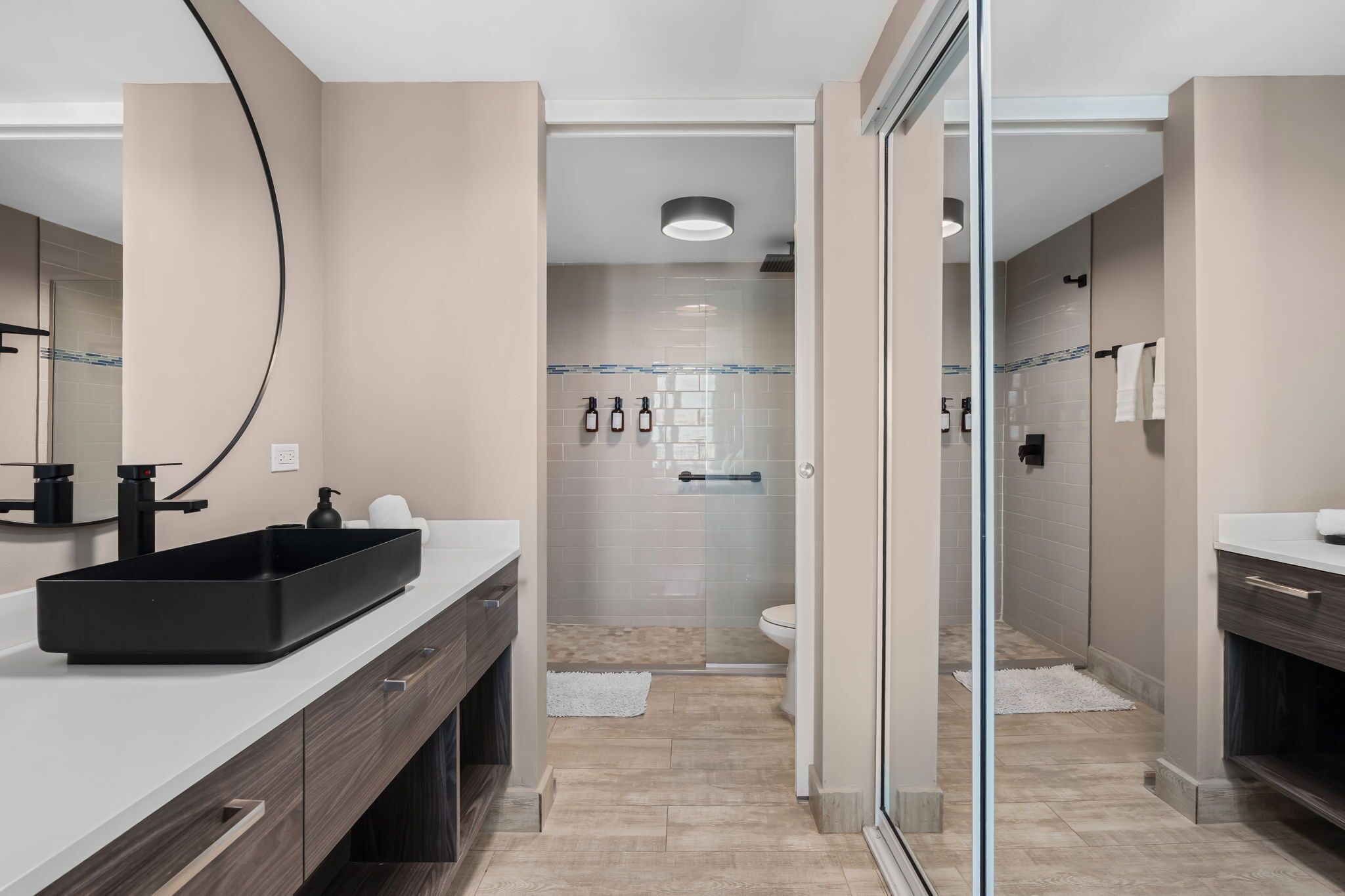 Un bagno moderno con lavandino nero, cabina doccia in vetro e vaso igienico bianco.