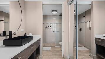 Un bagno moderno con lavandino nero, cabina doccia in vetro e vaso igienico bianco.