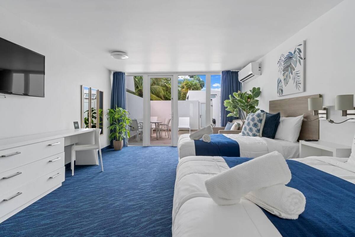 Habitación de hotel moderna con una cama grande, un escritorio, un televisor de pantalla plana y una puerta corrediza de vidrio que da a un área exterior.