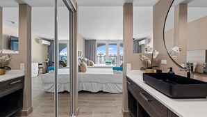 Habitación de hotel moderna con una cama grande, un lavabo negro, un espejo y vistas a la ciudad.