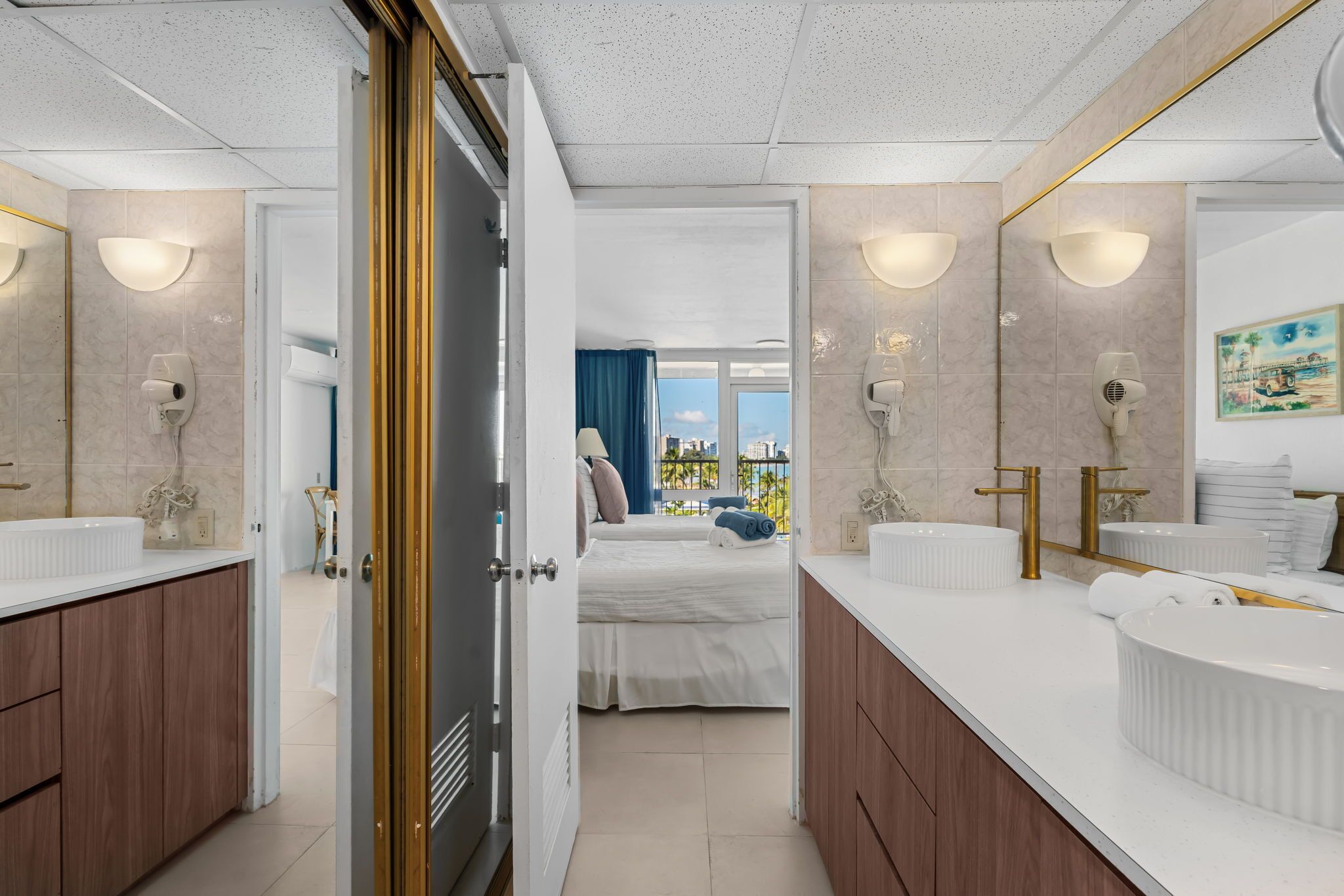 Habitación de hotel moderna con una cama grande, dos baños, vistas a la ciudad y un balcón.