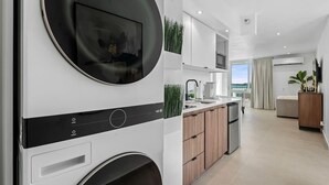 Cocina moderna con lavadora y secadora integradas, armarios de madera y un ventanal con vistas.